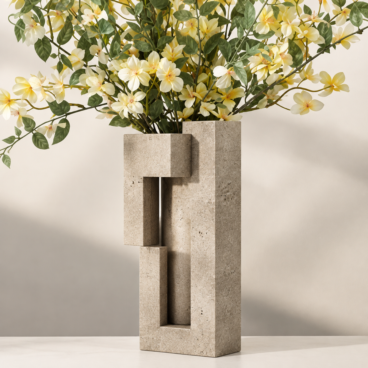 PLIOXOO® travertine vase top-down angle view on stone surface with plant leaves – Thoughtful Details: Beauty in Every Angle, showing internal interlocking rectangular channels